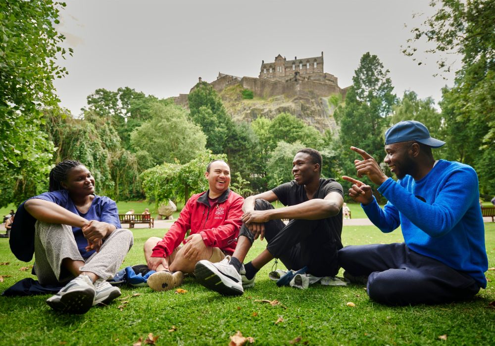 Four young people relax on the grass.