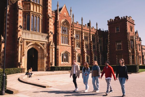 A group of students walking together in front of Queen's University Belfast