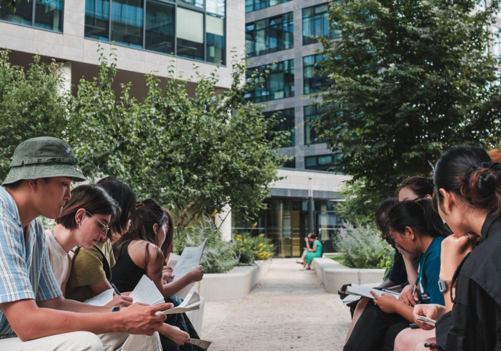 A group of people sitting on the grass, engaged in reading books.
